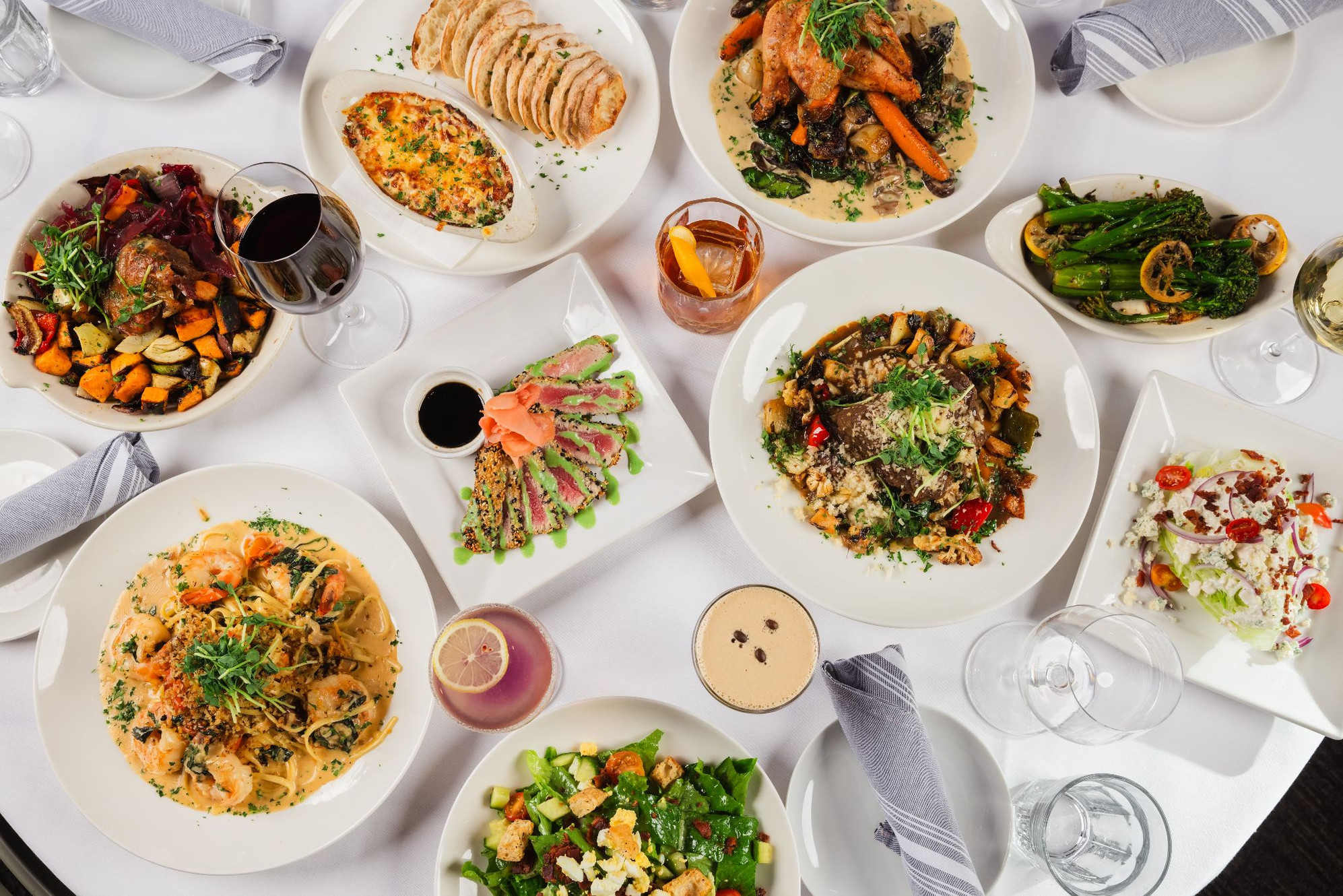 Dishes and cocktails on a table at a Rooted Hospitality Group restaurant